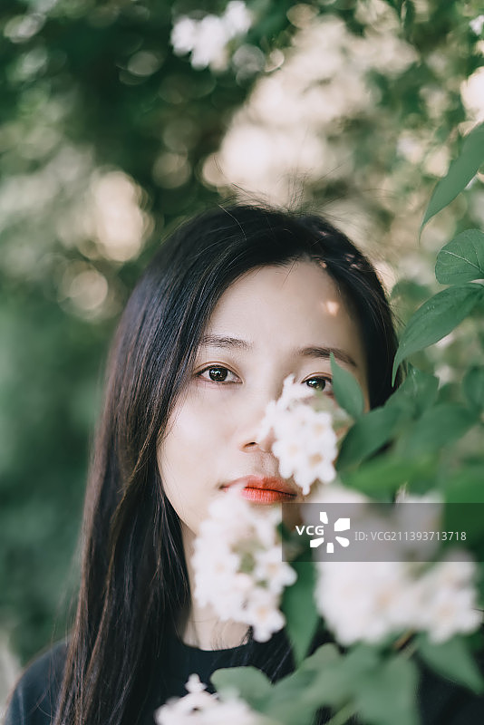 森系气质女孩在鲜花后甜美地微笑图片素材