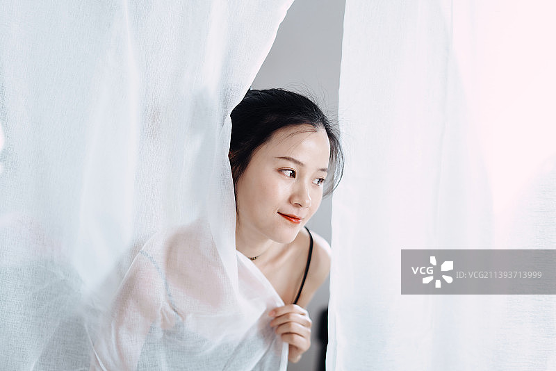 阳光下白色窗纱前的美丽女孩图片素材