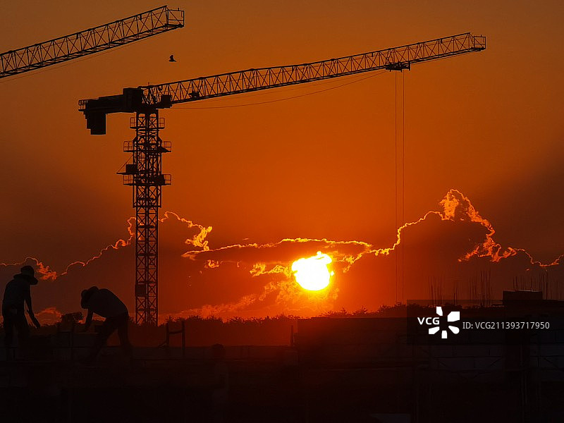 夕阳西下的天空衬托出建筑物及民工的轮廓图片素材
