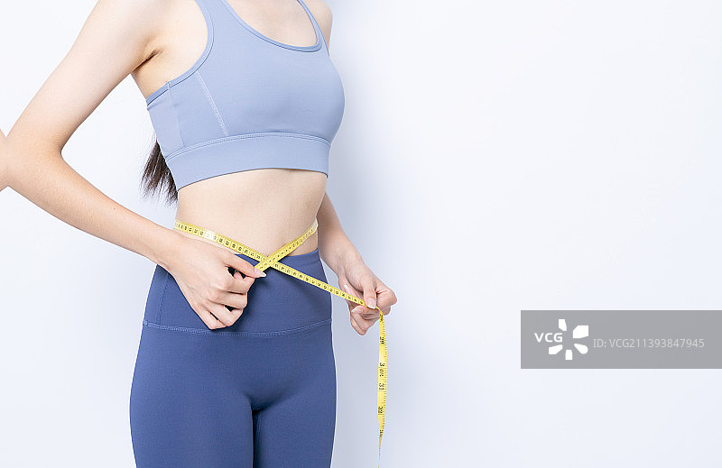 用尺子测量腰围的年轻女性图片素材