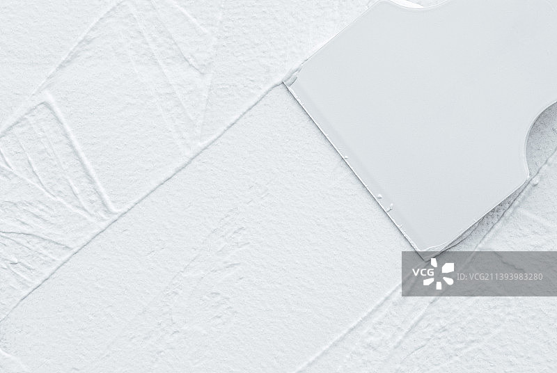 刮铲在墙上涂抹白色腻子，留白图片素材