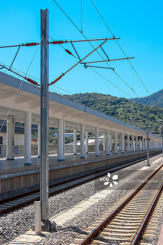 晴天阳光中有大山背景的动车站月台和轨道风景图片素材