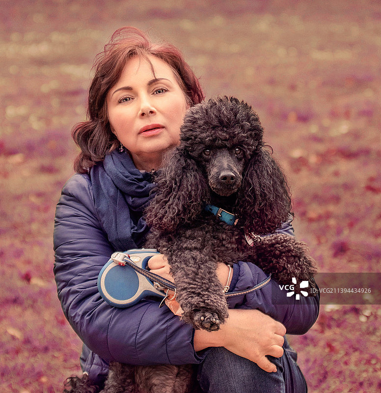 与黑色贵宾犬互动的女子肖像图片素材