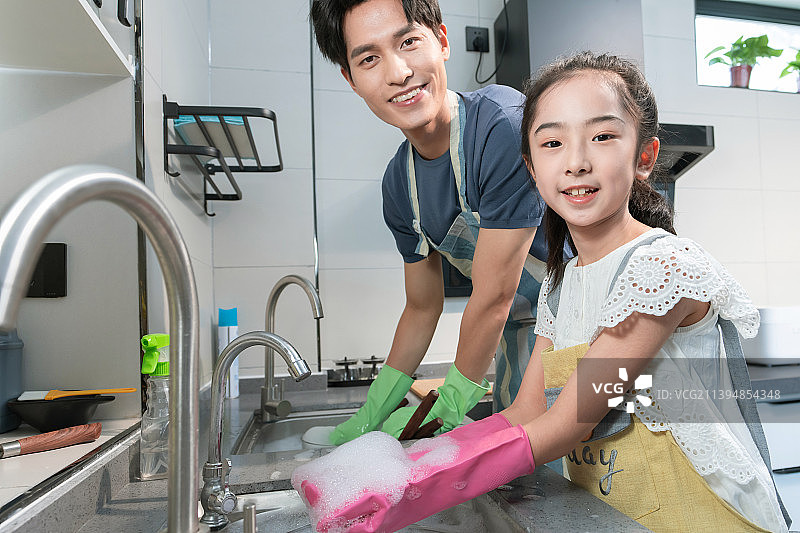 年轻爸爸教女儿刷碗图片素材