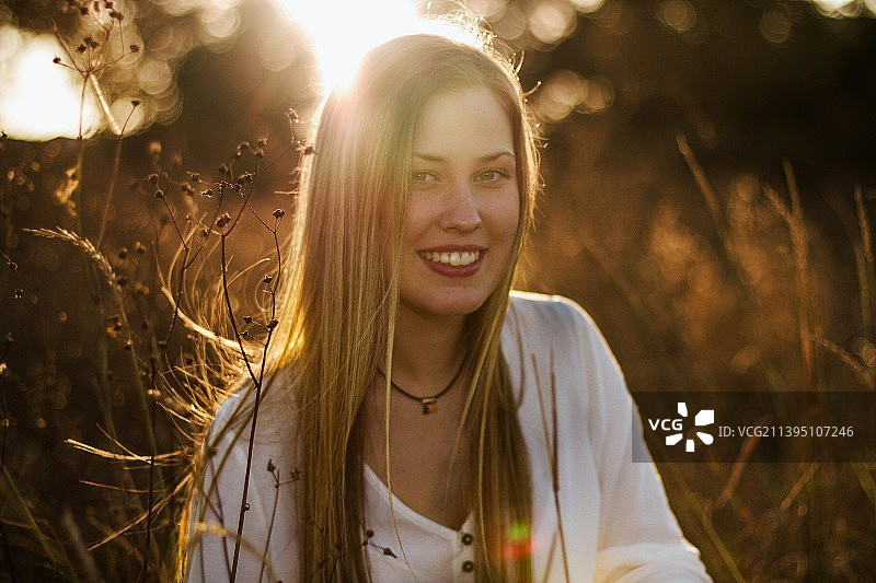 坐在田野上微笑的年轻女人肖像图片素材