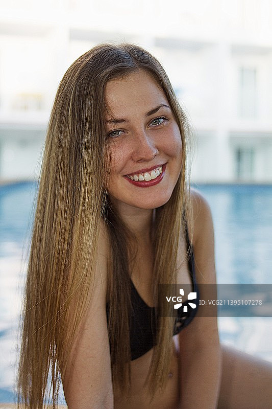 坐在马德里游泳池边的微笑年轻女子肖像图片素材