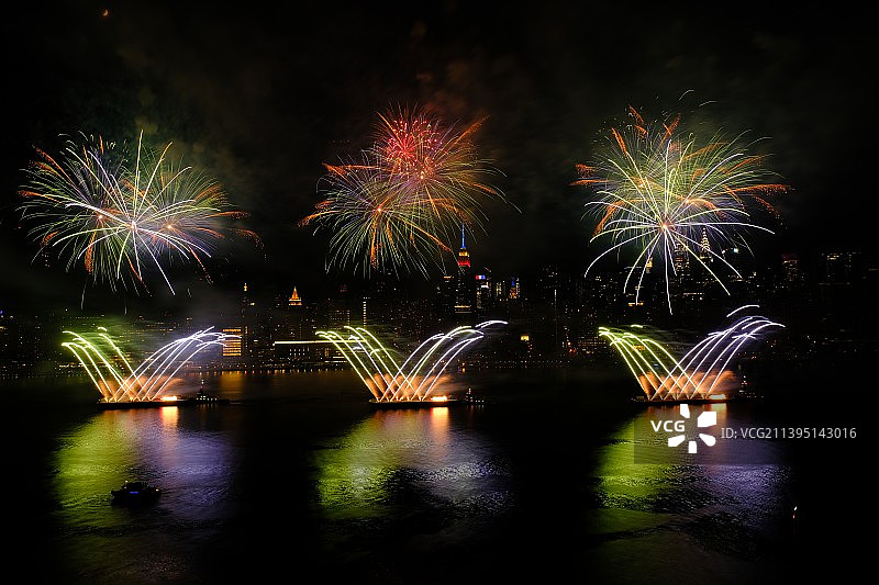 低角度拍摄夜空中河流上的烟花表演图片素材