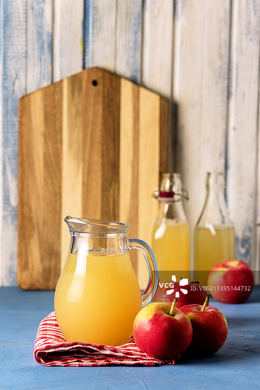 健康有机苹果汁，带水罐和瓶子的餐巾，红色苹果垂直秋收图片素材