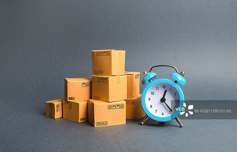 一摞纸板箱和一个蓝色闹钟。图片素材