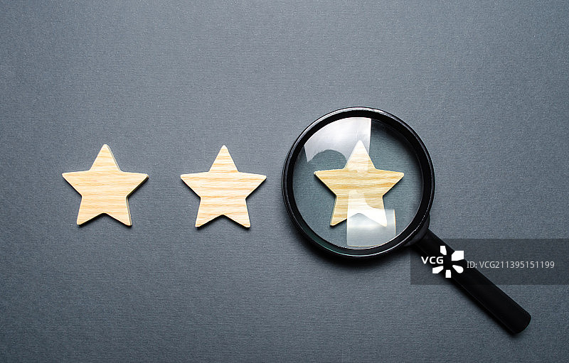 灰色背景上的三颗星星和一个放大镜图片素材