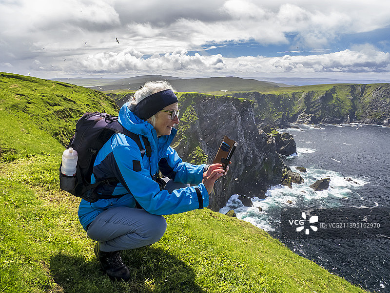 女子在英国设得兰群岛赫曼内斯拍摄北方塘鹅图片素材