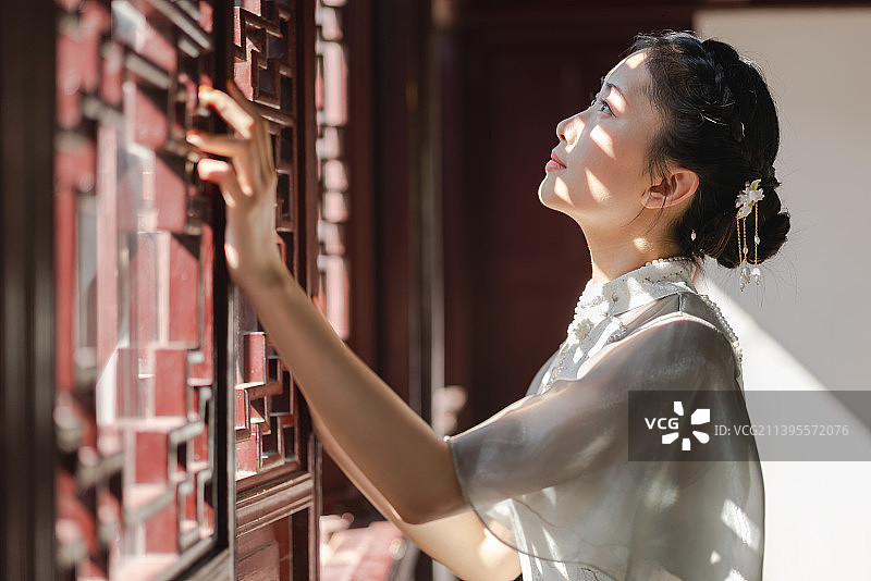 身穿旗袍在庭院散步的年轻女孩图片素材