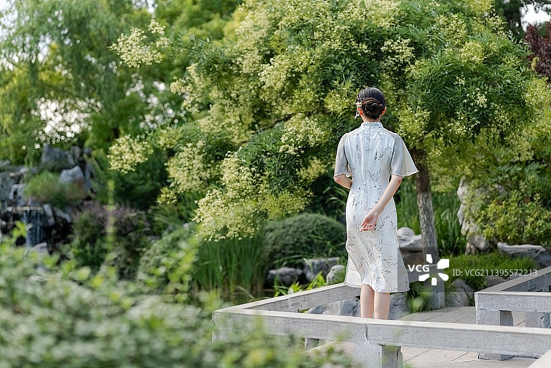 身穿旗袍在庭院散步的年轻女孩图片素材