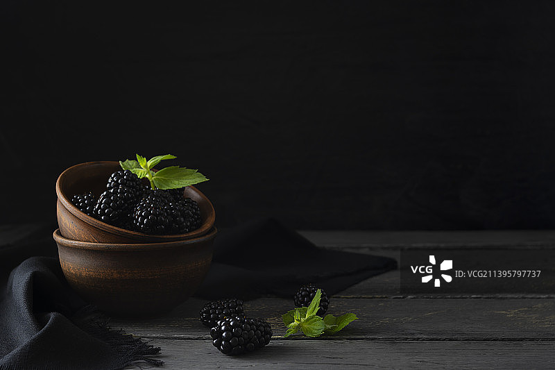 黏土碗中放在深色桌子上的大黑莓图片素材