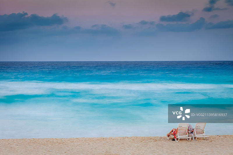 情侣在墨西哥坎昆加勒比海滩的日落时分放松图片素材