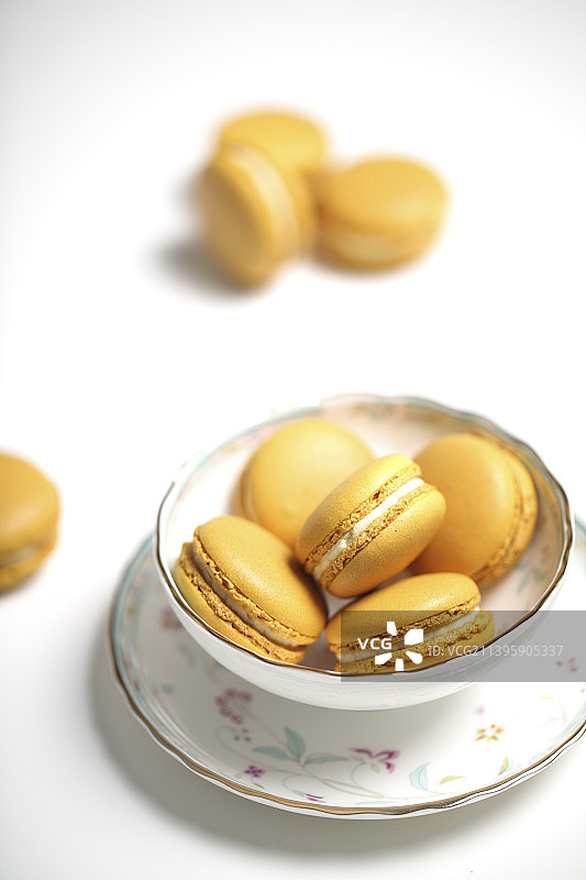 一组马卡龙图片 美食摄影 亮色调名色调 红茶杯里装满柠檬味黄色马卡龙甜品 夹心图片素材
