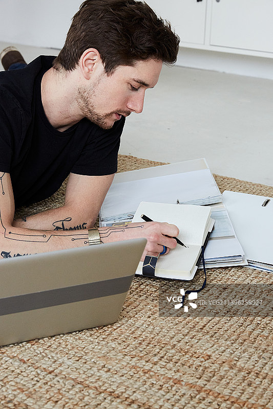 在地板上用笔记本电脑进行在线学习的中年男人肖像图片素材