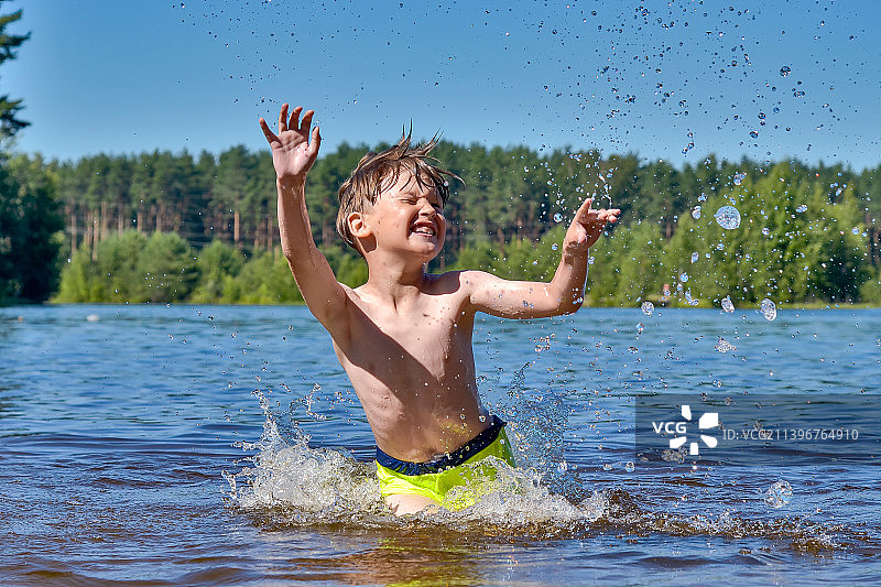 男孩在湖里向天空泼水，俄罗斯图片素材