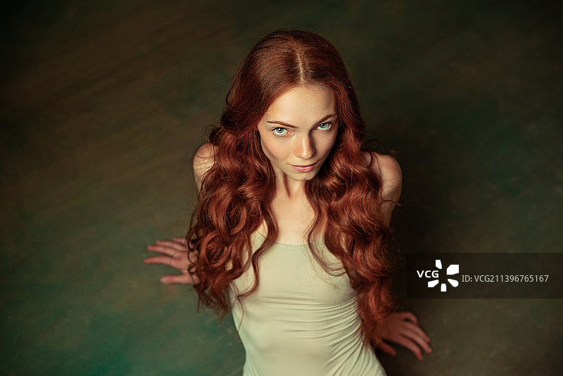 可爱的温柔红发女孩，长长的卷发在黑暗中显得格外突出图片素材