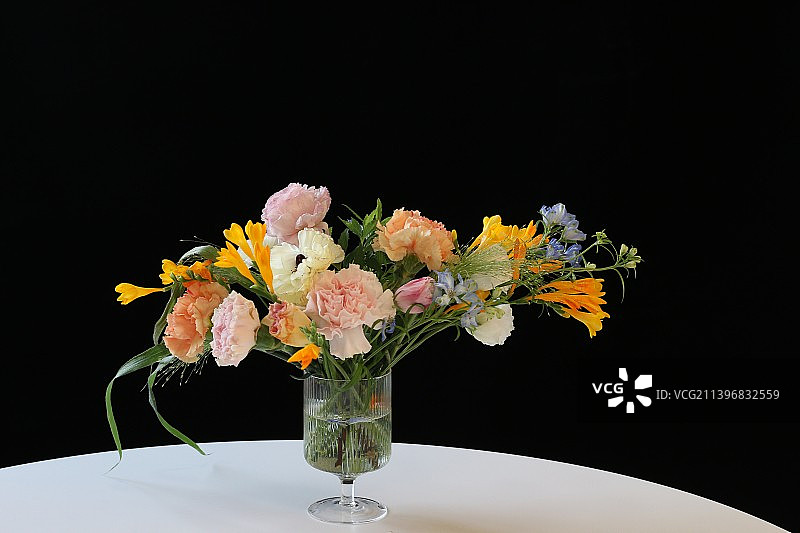 黑色背景下，花瓶中的花卉特写图片素材