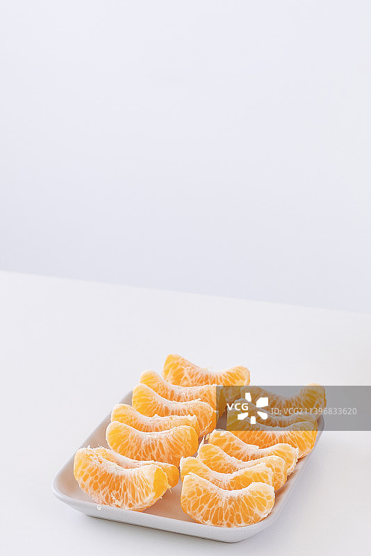 盘子里和金属篮子里去皮的美丽橘子，隔离在明亮的白色干净的桌子上图片素材