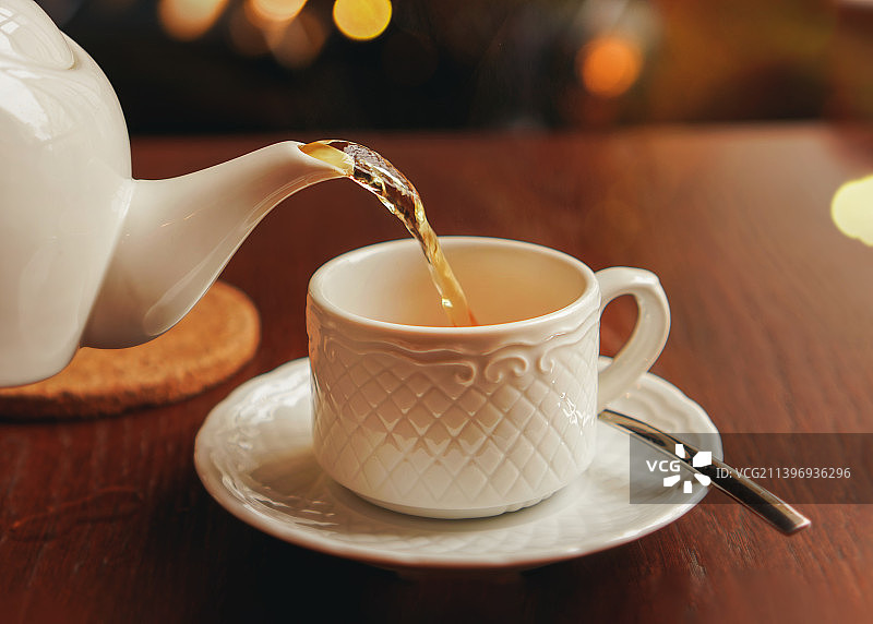 手持茶壶向白色杯子中倒茶图片素材