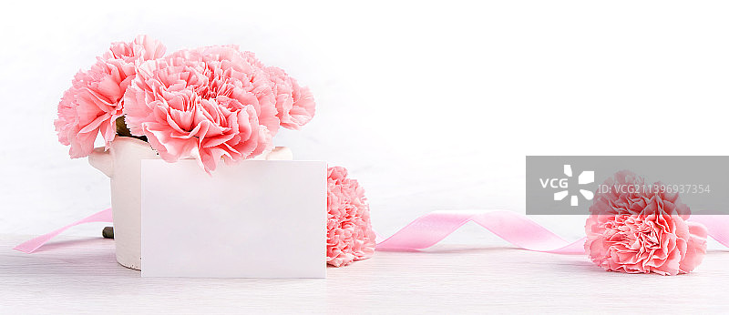 在明亮背景的白色花瓶中，盛开的粉红色娇嫩康乃馨图片素材