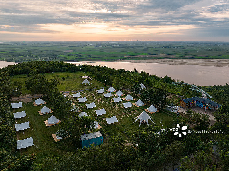 河南省郑州市黄河岸边日落晚霞下的黄河源景区露营基地图片素材