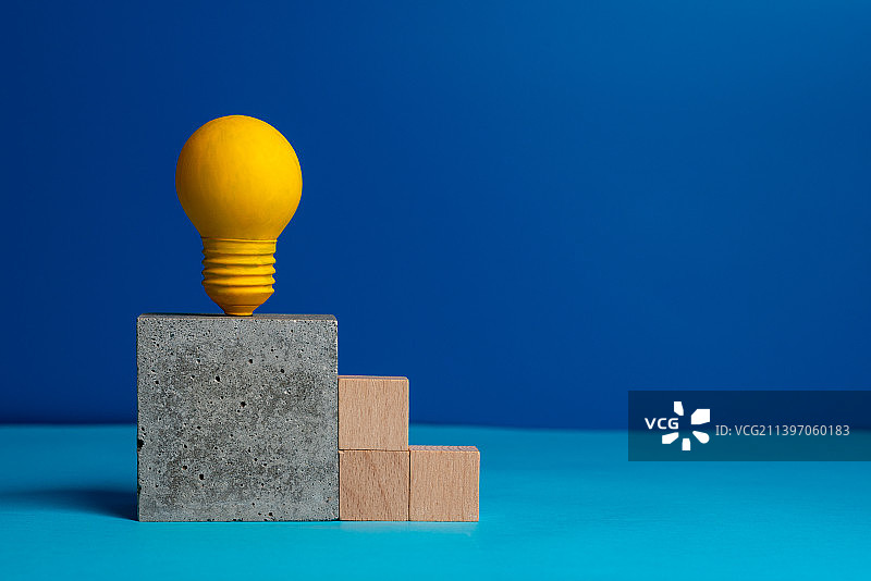 积木台阶和放在混凝土块上黄色的灯泡静物图图片素材
