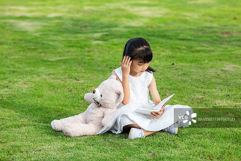 草地上一个中国小女孩在看书图片素材