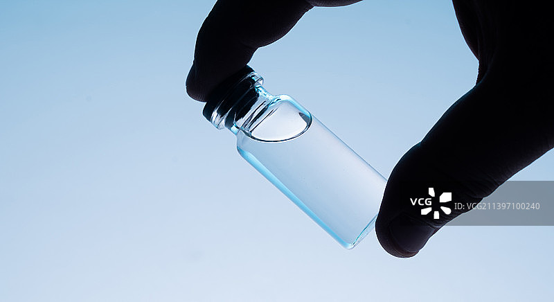 实验室中剪影手持玻璃容器图片素材