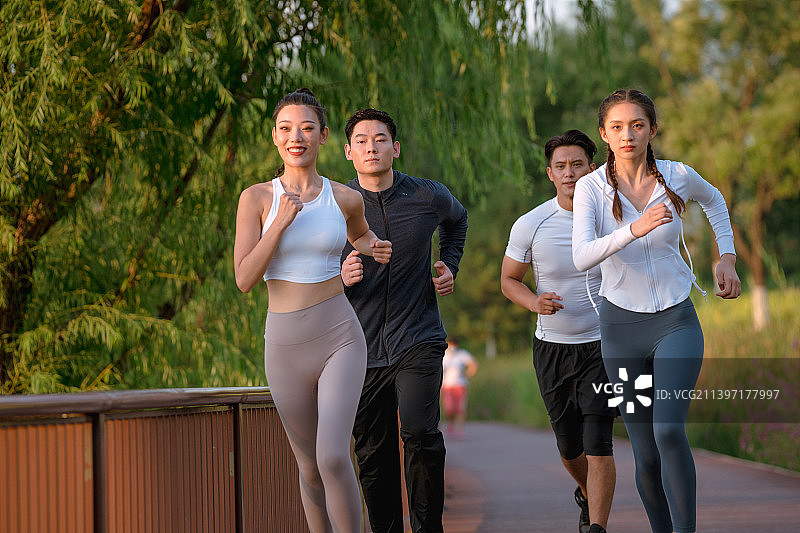 四个年轻人在城市公园里跑步图片素材