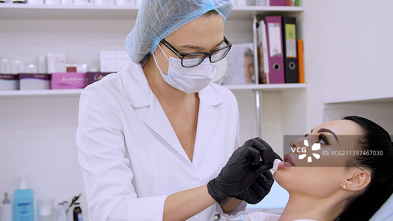 诊所美容室内医生正在擦拭患者的嘴唇图片素材