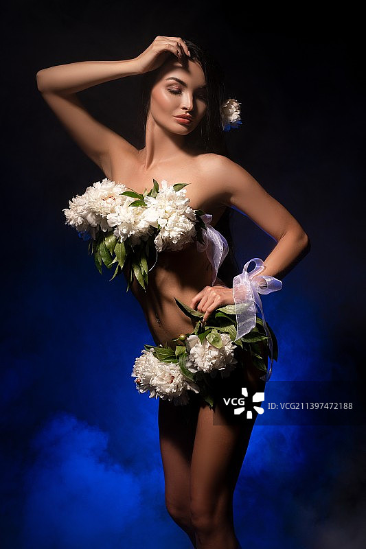 性感的女性与白色花朵的身体站在黑暗的工作室图片素材