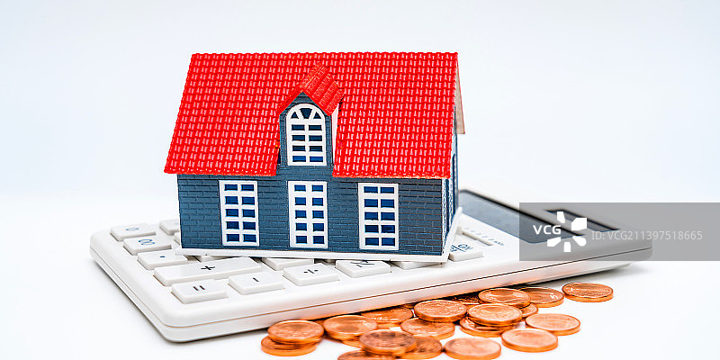 白色背景下的房子模型、计算器、钱币——买房概念图片图片素材