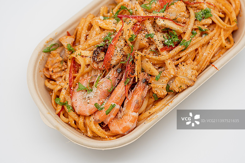 白色背景下餐盒里海鲜意面的特写镜头图片素材