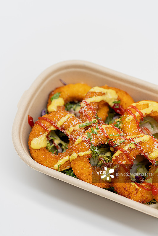 白色背景下餐盒里洋葱圈特写镜头图片素材