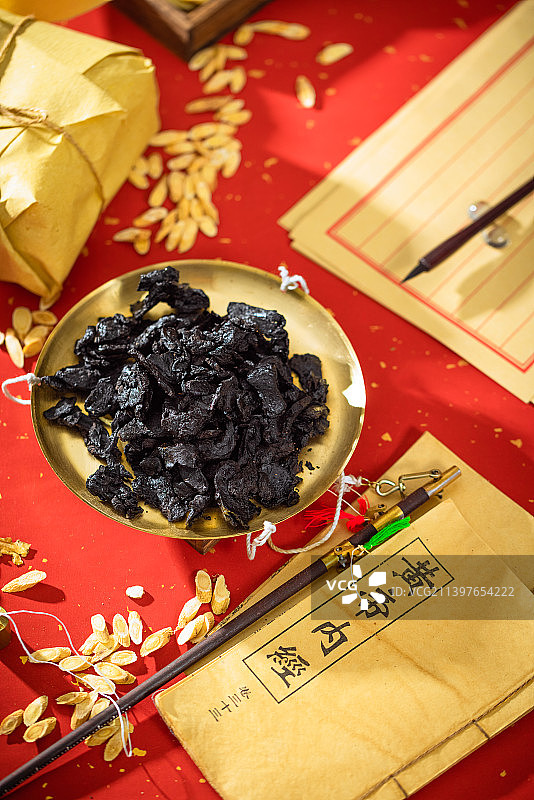 放在金色秤盘子里的中药熟地黄，本子上写的汉字是“黄帝内经”图片素材