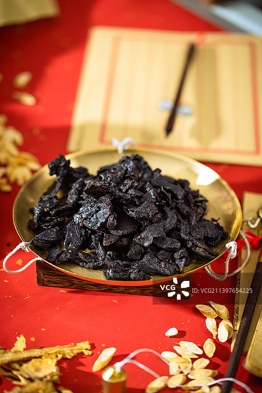 放在金色秤盘子里的中药熟地黄，本子上写的汉字是“黄帝内经”图片素材