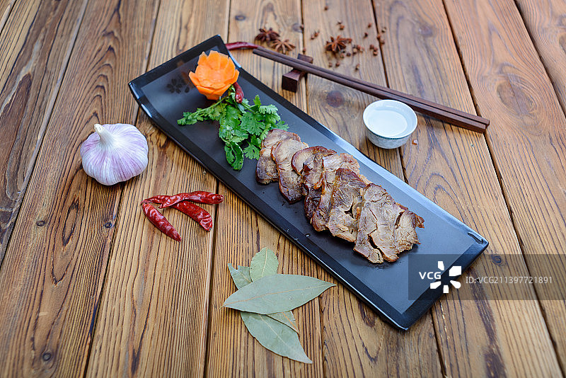 黑色盘子里的酱牛肉和白酒酒杯放在木桌上图片素材