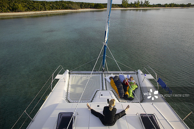 母亲看着孩子们在双体船船头睡觉图片素材