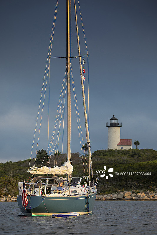 女人在岸边灯塔附近的帆船上放松图片素材
