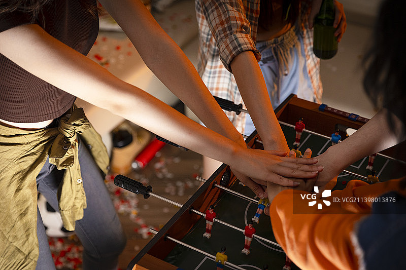 年轻朋友们一起叠手，准备玩桌上足球图片素材