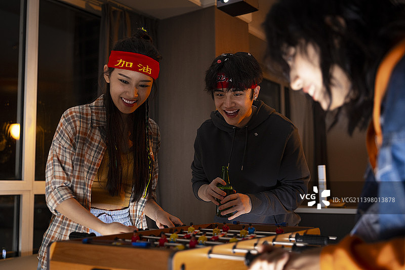 快乐的年轻人在客厅玩桌上足球图片素材