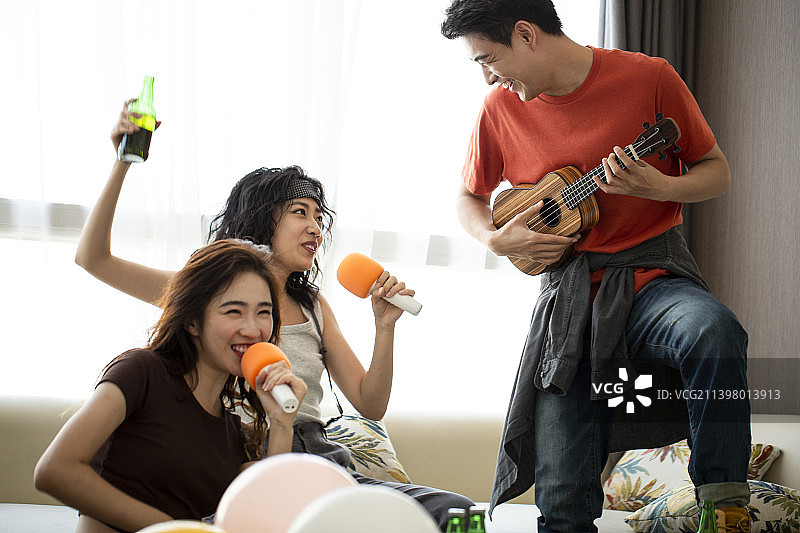 年轻朋友在家唱卡拉OK、喝啤酒嬉戏玩耍图片素材