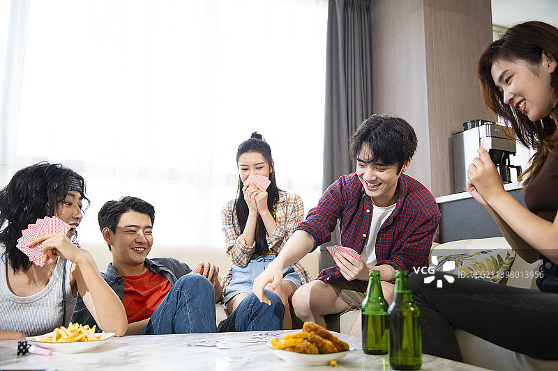 年轻朋友们在家里聚会打牌图片素材