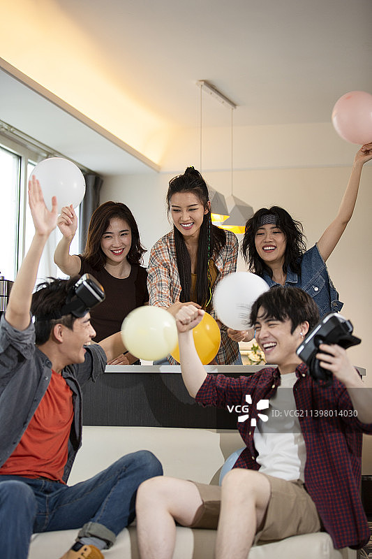 年轻朋友们在家里聚会玩VR游戏打闹嬉戏，庆祝成功图片素材