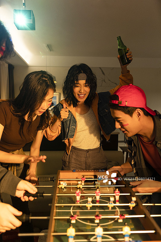 快乐的年轻人在客厅玩桌上足球图片素材