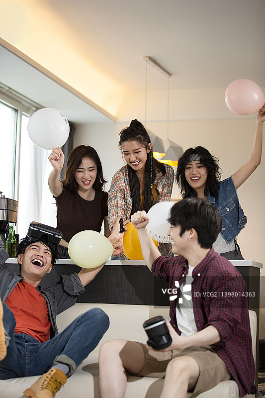 年轻朋友们在家里聚会玩VR游戏打闹嬉戏，庆祝成功图片素材