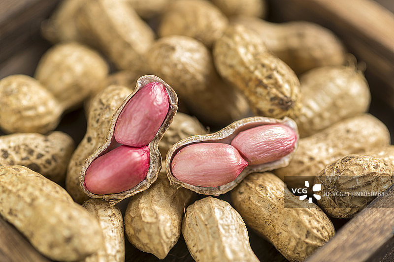 一簸箕鲜花生特写木桌面黑色背景图片素材